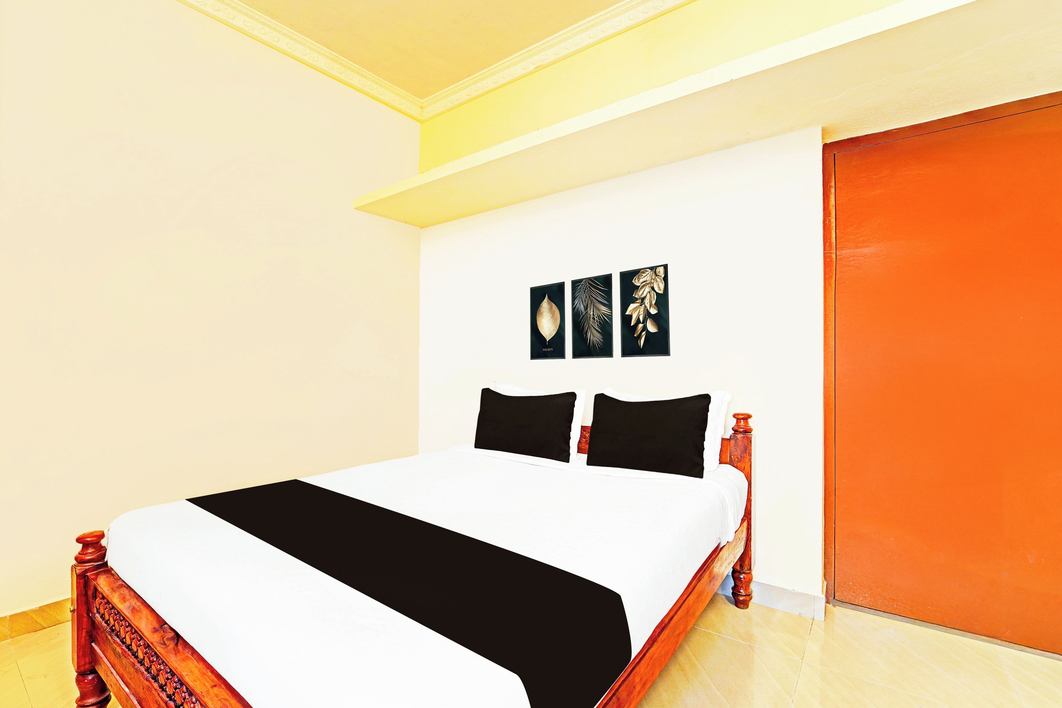 A room with a bed, a door, and three wall-mounted pictures.