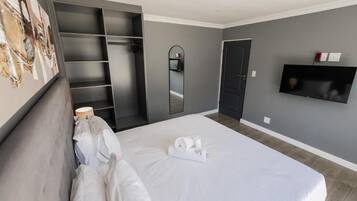 Una habitación de hotel con una cama, un armario, un espejo y un televisor.