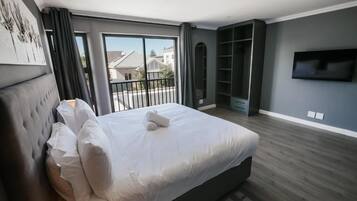 Un dormitorio moderno con una cama grande, una televisión y un balcón con vistas a casas.