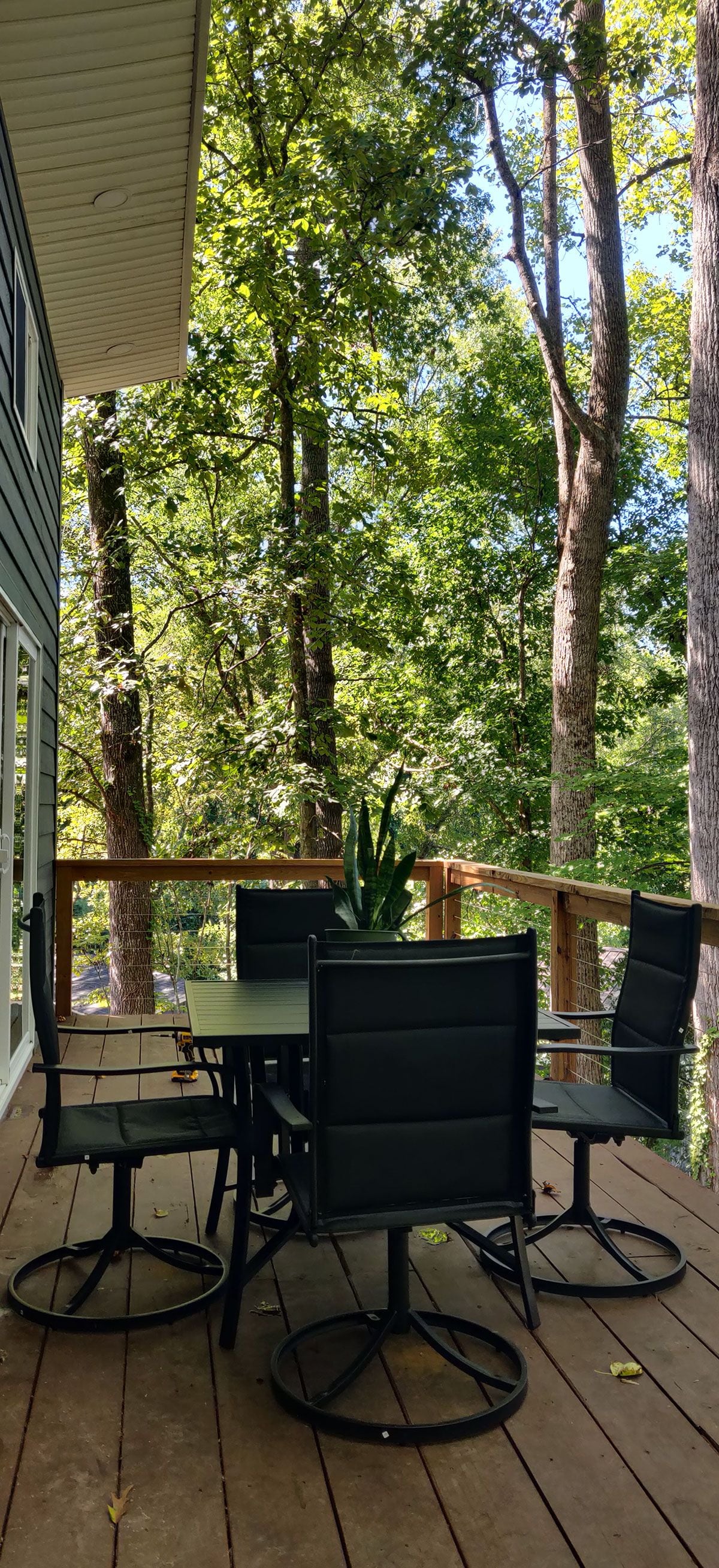 An outdoor deck with a table and chairs, surrounded by trees.