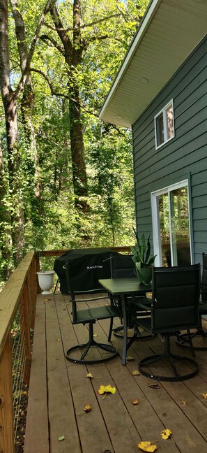 A wooden deck with outdoor furniture, a covered grill, and a view of a house with a window. - Hill Top Cabin overlooking The Pond! (Granite Falls)