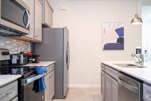Een moderne keuken met roestvrijstalen apparatuur, een magnetron, een koffiezetapparaat en een vaatwasser.