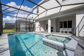 A swimming pool with a glass enclosure, a hot tub, and outdoor seating. - Windsor Cay 7BR | Themed rooms, pool & spa (Clermont)