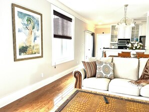 A living room with a sofa, a coffee table, and a painting on the wall. - Shadow Brooke Village Unit 100 • FLETC & Vacation 3BR Condo w/Garage (St. Simons Island)