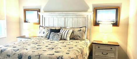 A bedroom with a bed, nightstands, a headboard, and wall-mounted lamps.