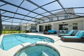 A covered outdoor swimming pool with lounge chairs and a patio area. - 7BR near Disney | Private pool, spa, game room (Kissimmee)