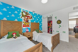 Een kinderkamer met twee bedden, een muurschildering en een dartbord.
