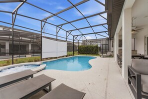 A pool area with a hot tub, lounge chairs, and a pergola structure. - 9BR themed home | Pool, arcade & cinema (Orlando)