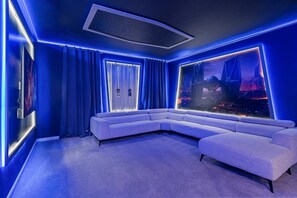 A room with a sectional sofa, a starry ceiling, and a large wall mural. - 9BR themed home | Pool, arcade & cinema (Orlando)
