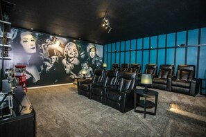 A home theater room with a large wall mural, leather recliners, and a carpeted floor. - 7BR Kissimmee home | Pool, cinema, games (Kissimmee)