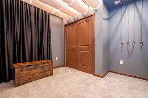 A room with a closed wooden door, a dark curtain, a wooden chest, and a wall-mounted rope. - 9BR Solara home | Pool, spa & themed rooms (Kissimmee)