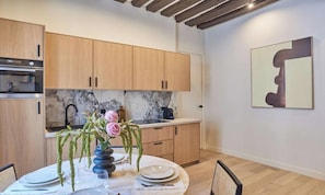Eine moderne Küche mit Holzschränken, einer Marmor-Spritzschutzwand und einem Essbereich mit Tisch für zwei Personen.