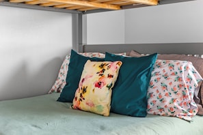 A bed with floral bedding, teal pillows, and a wooden headboard. - NEW! Fall Hill Country | Hot Tub, Pool, Sleeps 11 (Dripping Springs)