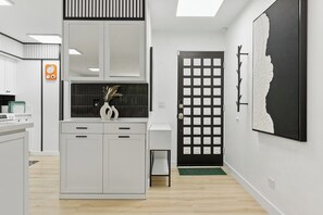 Une cuisine moderne avec des meubles blancs, une porte noire et un tapis vert.