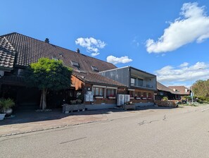 A street view with a two-story building featuring a tiled roof, a wooden facade, and a small balcony. - Waldblick Apartment, Quiet, Emmental, Solothurn & Bern (Kernenried)