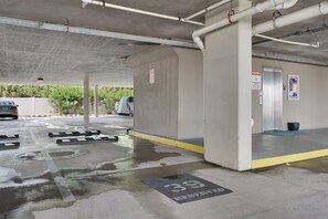 Un aparcamiento con suelo mojado, un coche y un vehículo cubierto.