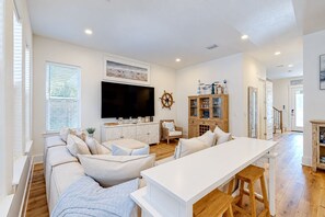 A spacious living area with a large flat-screen TV, a wooden cabinet, and a cozy seating arrangement. - ⛱️The Spotted Sandpiper | Walk 2 Beach | Community Pool☀️Pet Friendly (Miramar Beach)