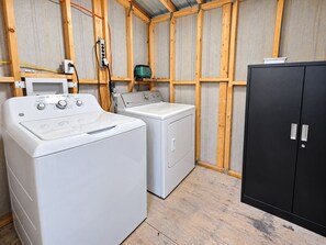 A laundry room with two washing machines, a dryer, and a black cabinet. - King Beds  Tampa Nature Hideaway Chic 2BR (Tampa)