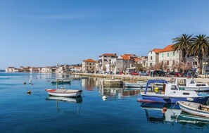 A coastal town with boats docked along the waterfront, stone buildings with red roofs, and a clear blue sky. - Studio apartment Milica in the stone house near the beach (Kaštel Novi)