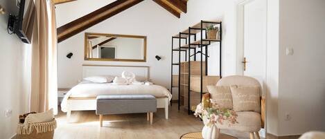 Un dormitorio con cama, un banco, una silla, una mesita, un espejo y un reloj en la pared.