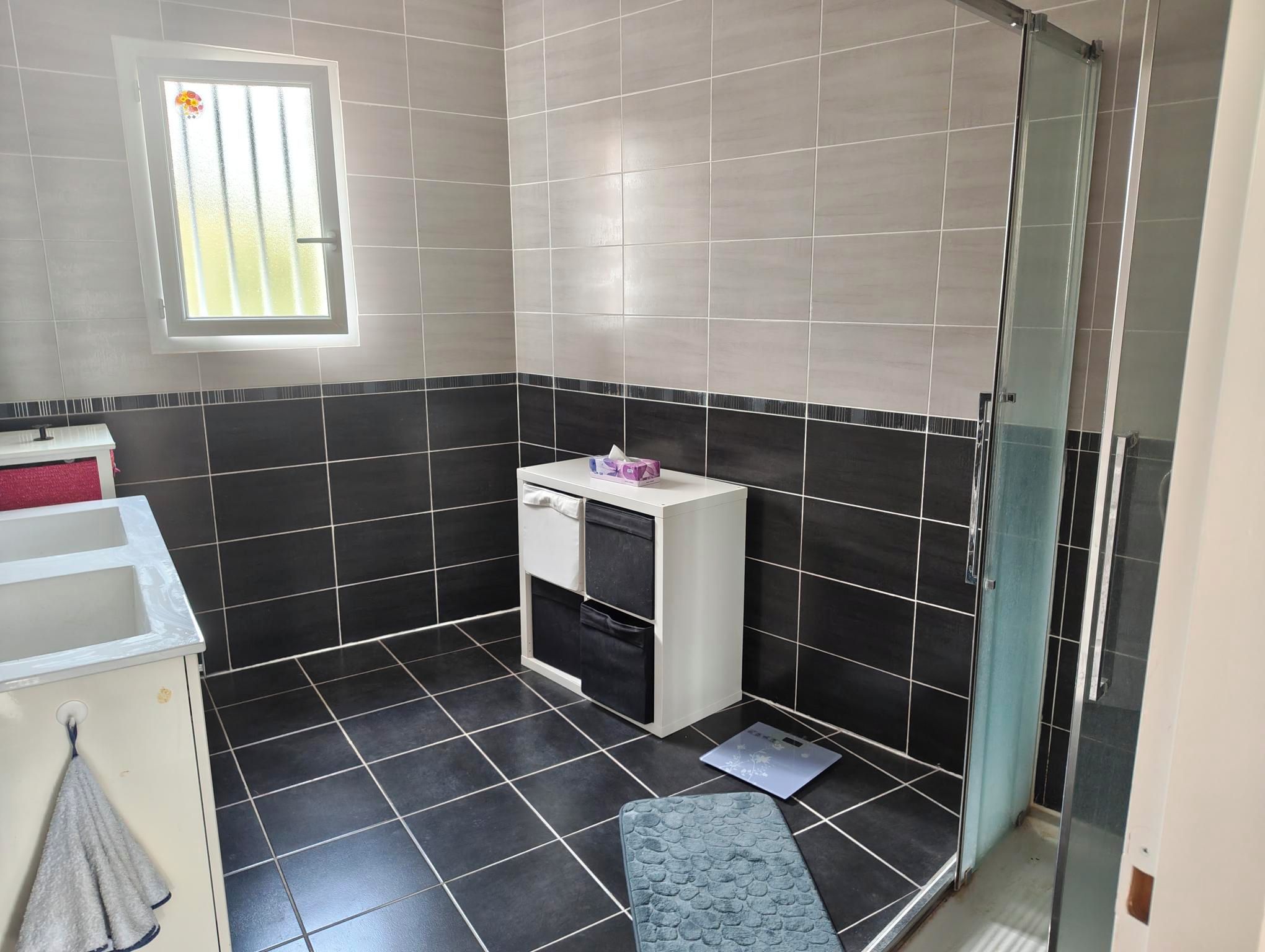 Une salle de bain avec des carreaux noirs et blancs, une porte de douche en verre, un lavabo blanc et un porte-serviettes.
