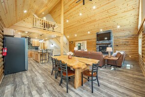 Ein Holzblockhaus-Interieur mit Essbereich, Küche, Wohnzimmer und einem Balkon.