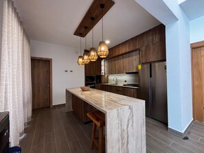 Een moderne keuken met een marmeren eiland, houten kasten en hanglampen.