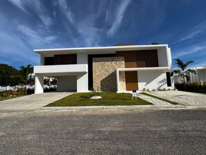 A modern two-story building with a flat roof, a stone facade, and a well-maintained lawn. - Brand-New 4-Bedroom Villa with Private Pool, SOV (Sosua)