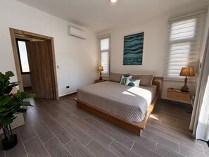 A bedroom with a bed, bedside tables, a potted plant, and a painting on the wall. - Brand-New 4-Bedroom Villa with Private Pool, SOV (Sosua)