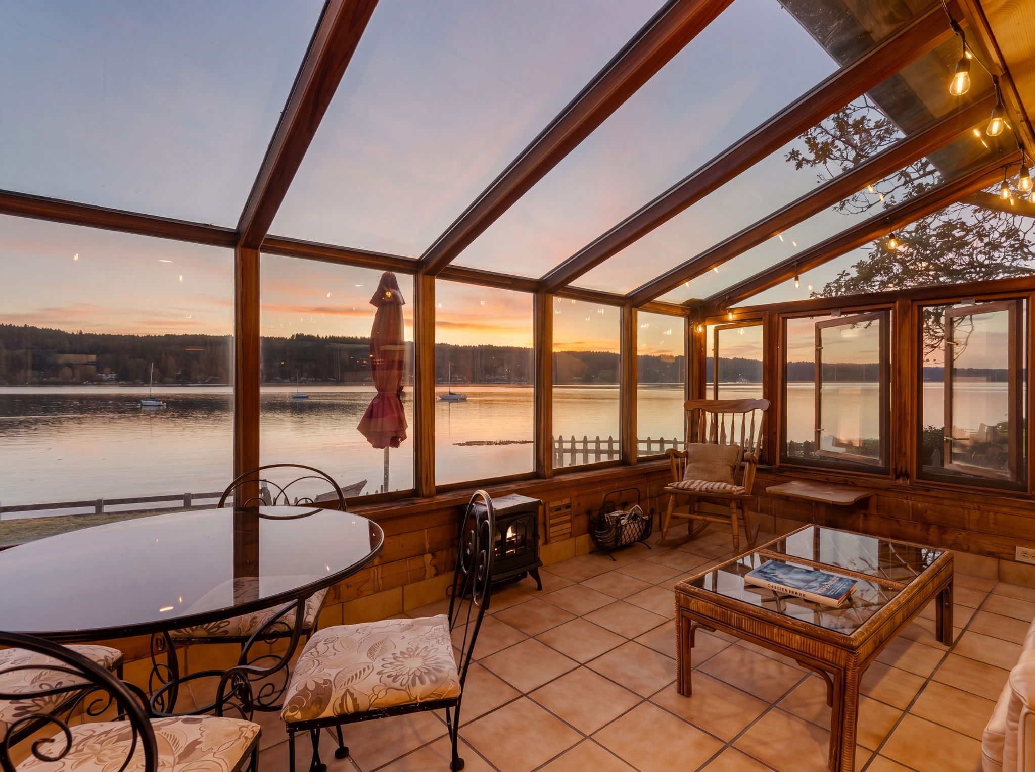 A sunroom with a view of a lake and a sunset.