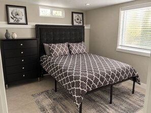 A bedroom with a bed, a dresser, and two framed floral pictures on the wall. - Serenity on Sherwood | Old Town, Dogs Welcome (Fort Collins)