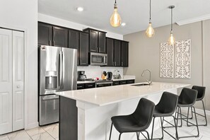 A modern kitchen with a central island, stainless steel appliances, black cabinets, and pendant lighting. - Magical Getaway with Private Pool, Top location (Four Corners)