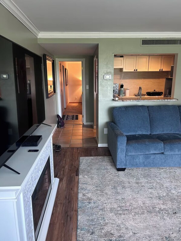 A compact living space with a kitchenette, a sofa, and a TV.