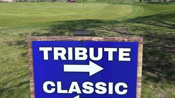Señal con indicaciones hacia 'TRIBUTE CLASSIC' en un campo de golf.