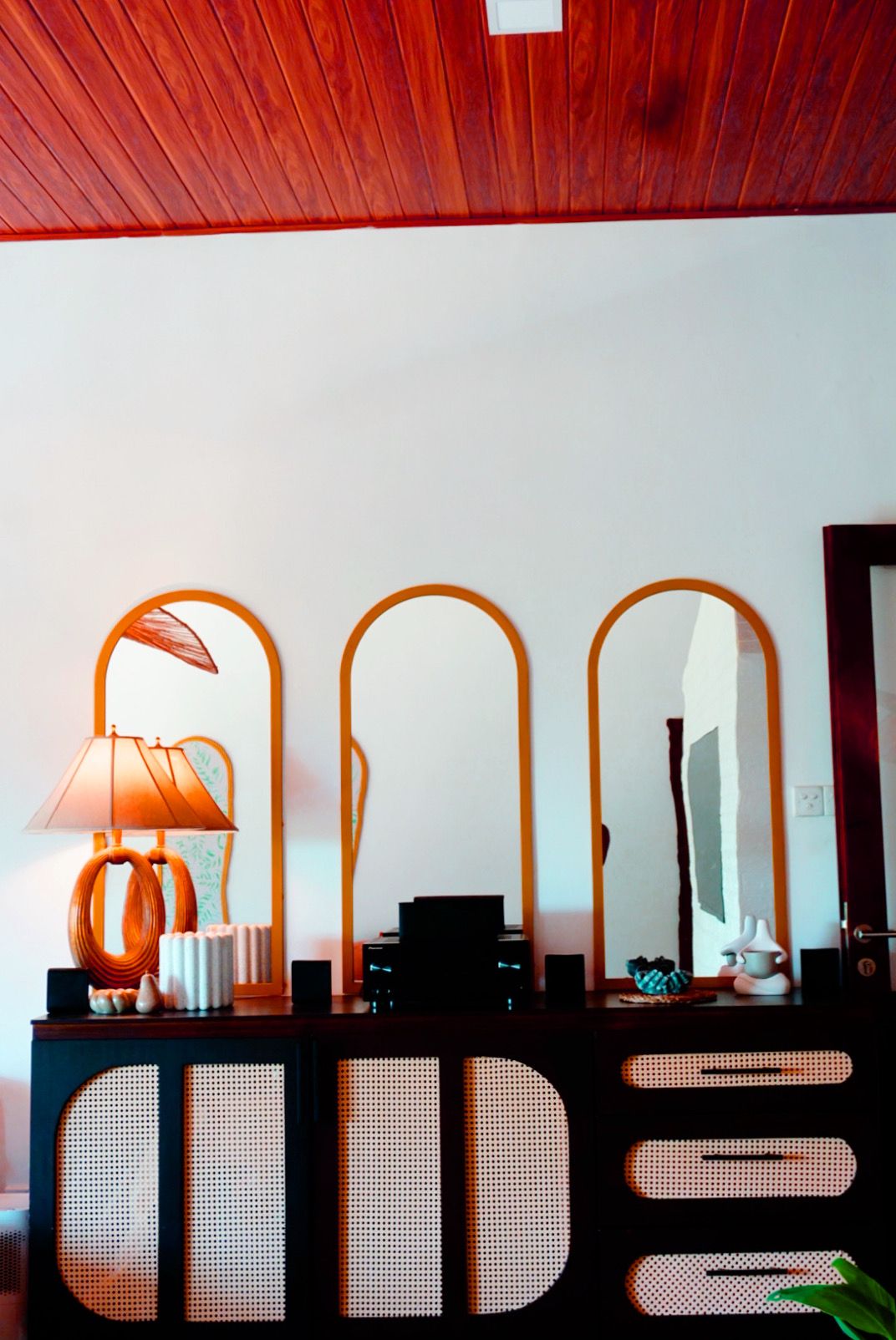 Una habitación con techo de madera, un espejo fijado a la pared, una lámpara y un sistema de sonido.