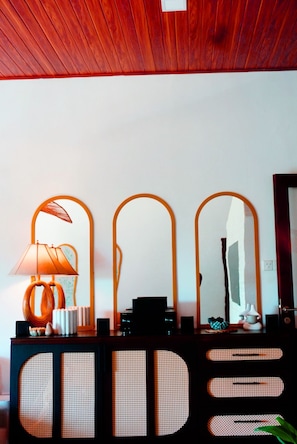 A room with a wooden ceiling, a wall-mounted mirror, a lamp, and a speaker system.