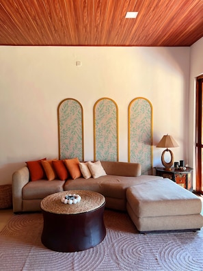 A living room with a sectional sofa, a round coffee table, and a side table with a lamp.