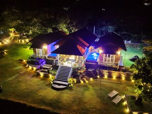 A two-story house with a swimming pool, outdoor seating, and a well-lit garden at night. - Riverston Glade (Laggala)