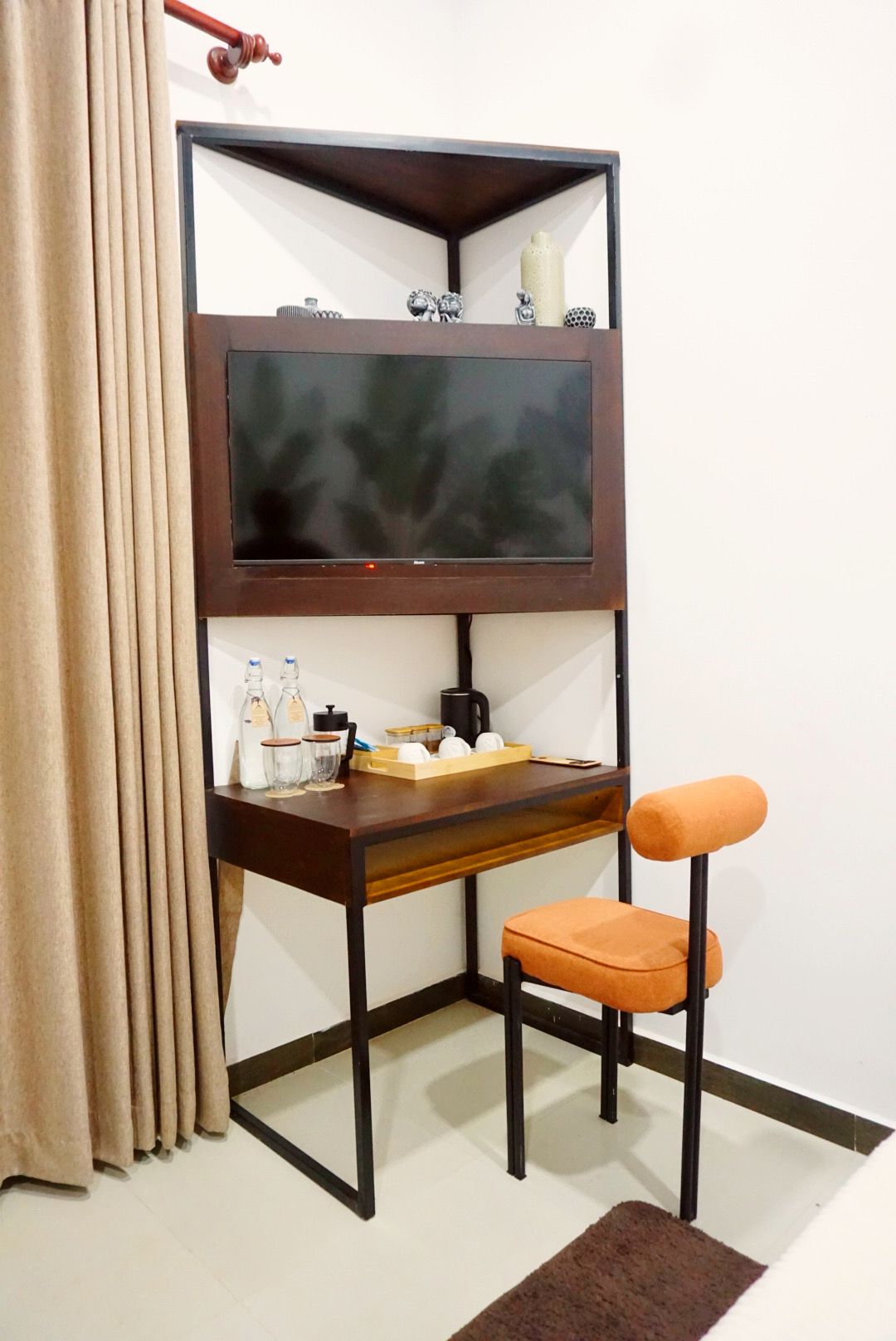 A bunk bed with a television, a desk with a chair, and various items on the desk.