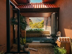 A covered outdoor area with a pool, potted plants, and a view of a mountainous landscape.