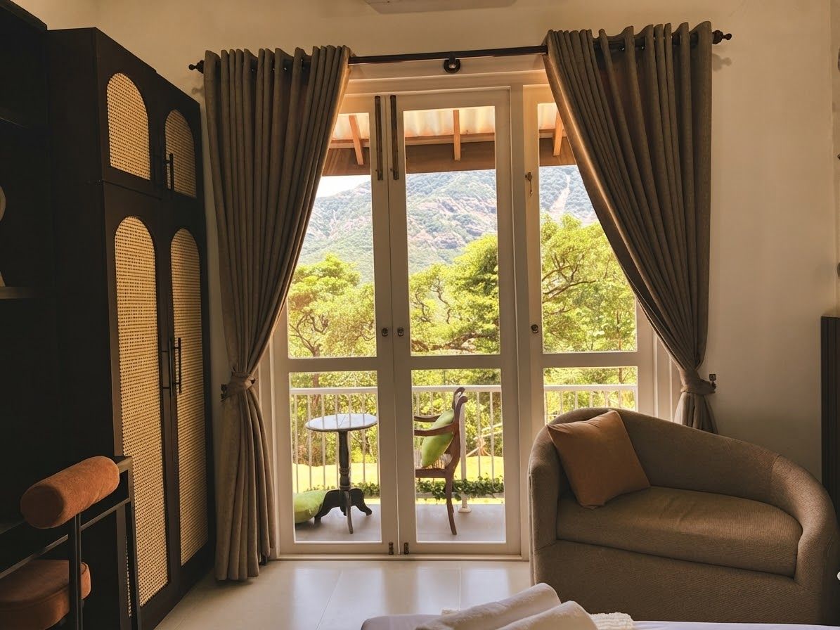 A room with a sofa, a table, and a view of a mountain landscape through large glass doors.