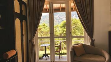 A room with a sofa, a table, and a view of a mountain landscape through large glass doors.