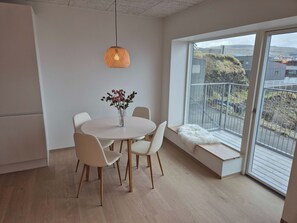 Ein moderner Essbereich mit einem runden Tisch, weißen Stühlen, einer Blumenvase und einer Pendelleuchte.
