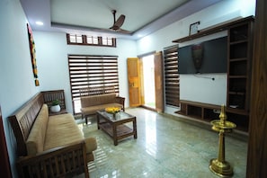 Una sala de estar con sofá, mesa de centro, televisor y una lámpara decorativa.