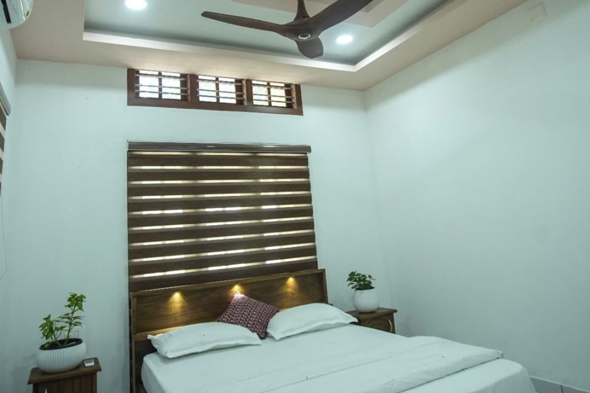 A bedroom with a bed, bedside tables, a ceiling fan, and a window with blinds.