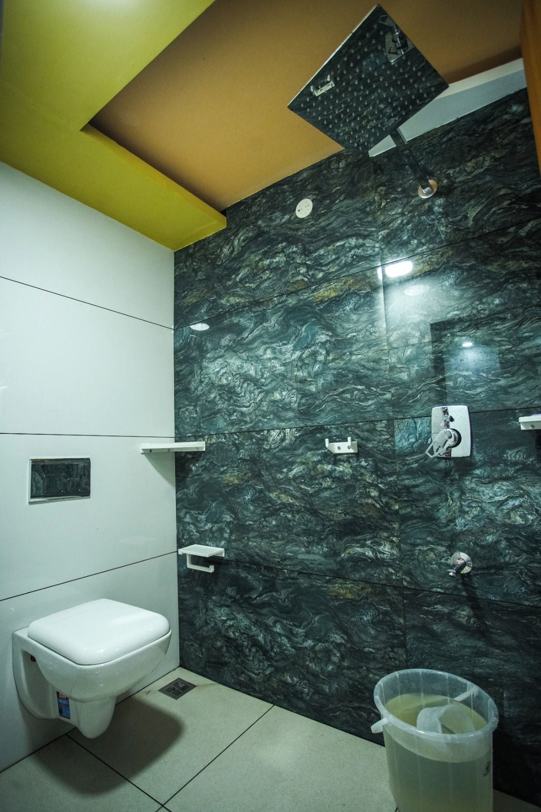 A bathroom with a toilet, a sink, and a shower area with a dark marble wall.
