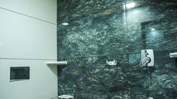 A bathroom with a toilet, a sink, and a shower area with a dark marble wall.