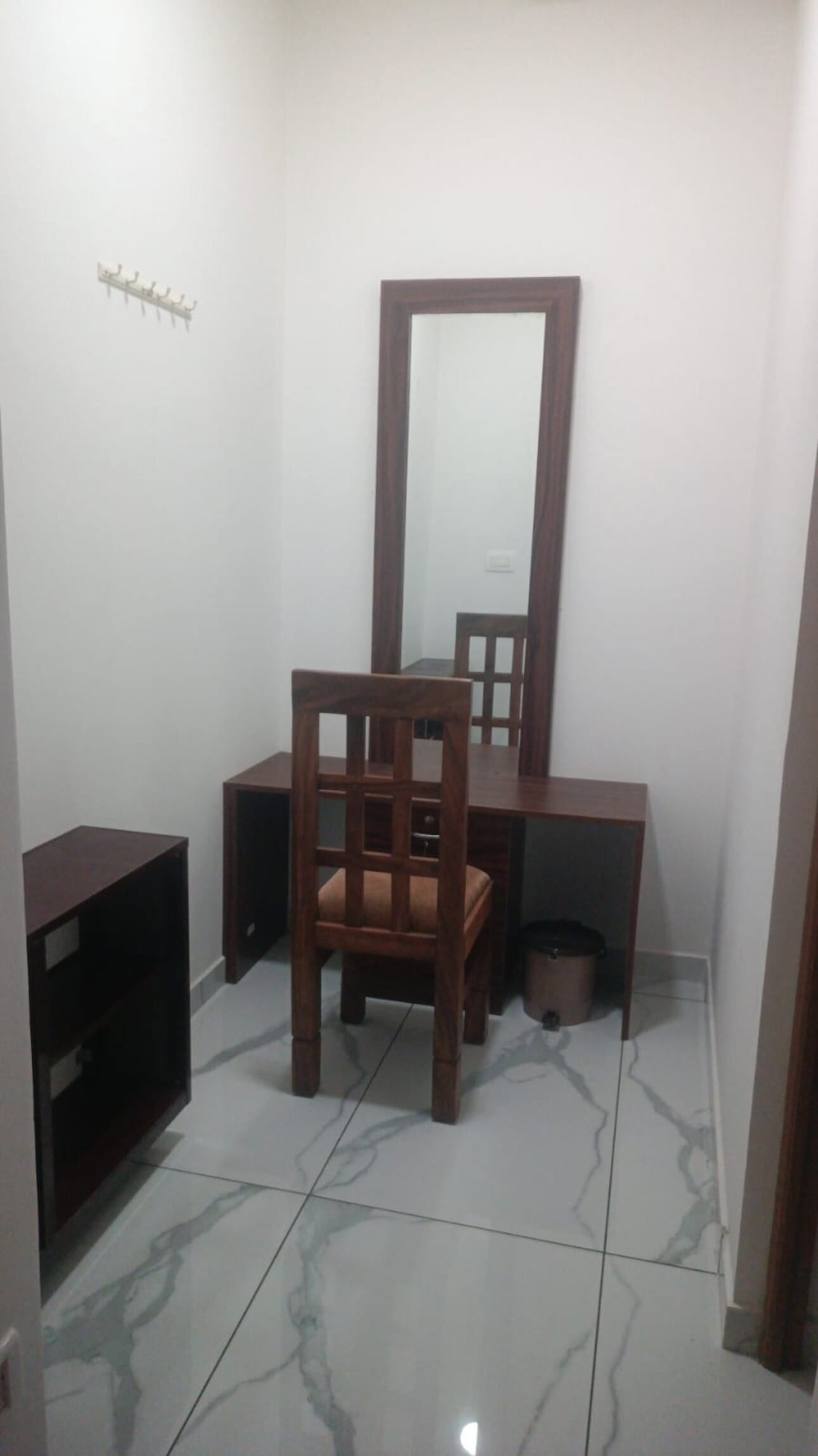 A small, enclosed room with a wooden desk, chair, and a mirror.
