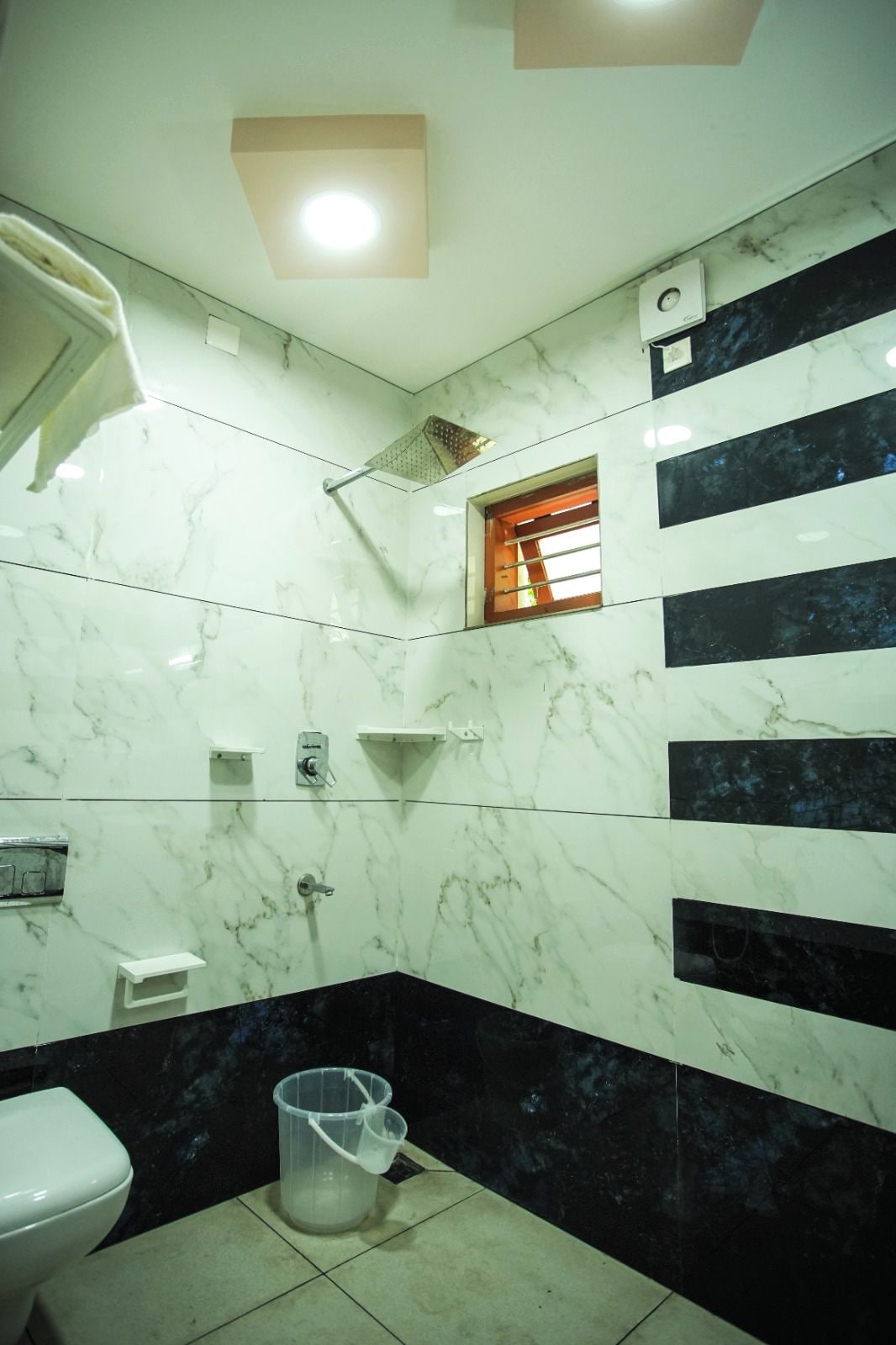 A bathroom with a toilet, a shower, a sink, and a trash bin.