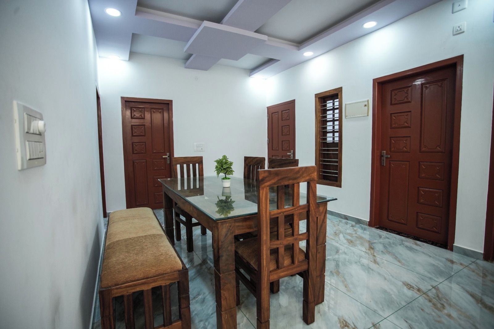 Un comedor con una mesa y sillas de madera, un banco y una planta en maceta.